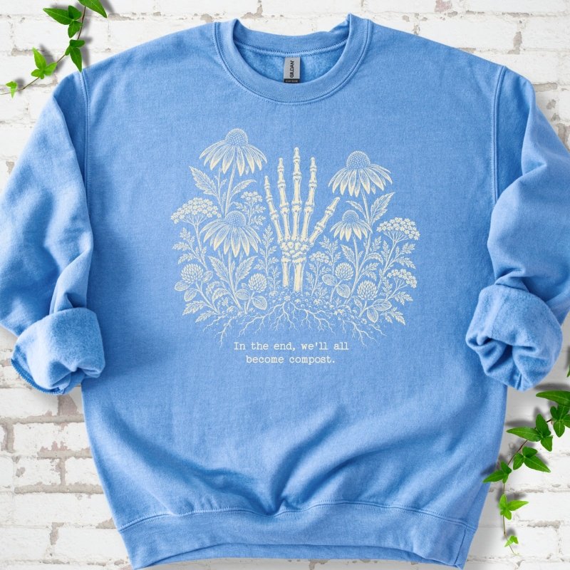 Carolina Blue classic sweatshirt featuring a cream botanical skeleton-hand graphic reading In the end, we'll all become compost
