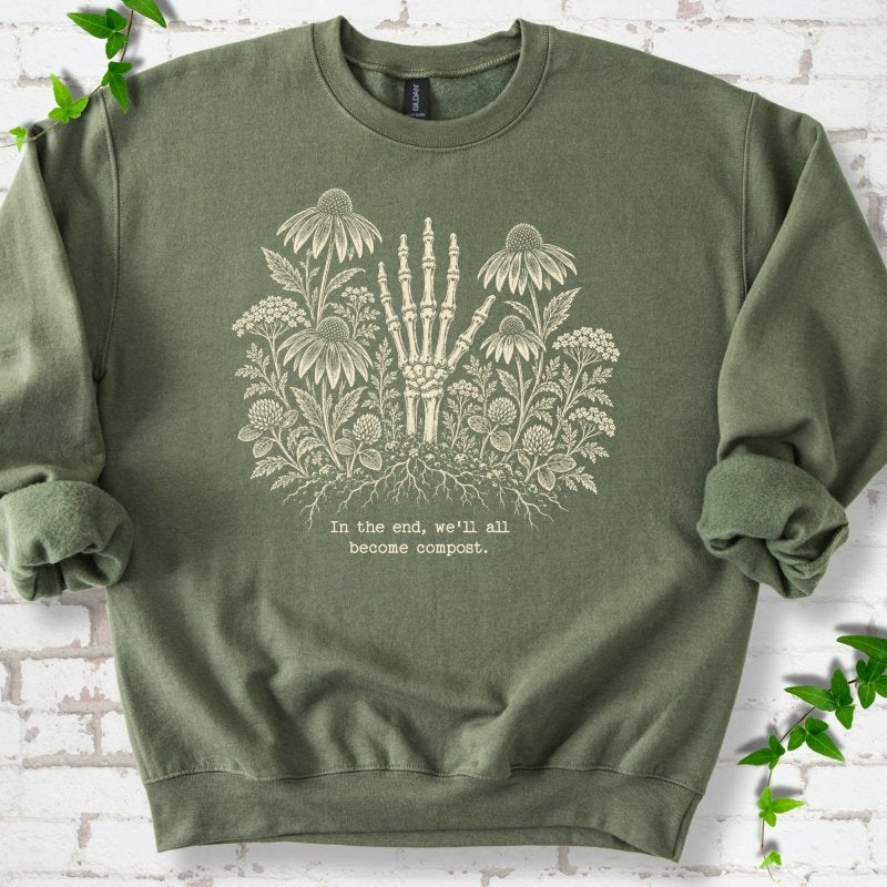 Military Green classic sweatshirt featuring a cream botanical skeleton-hand graphic reading In the end, we'll all become compost