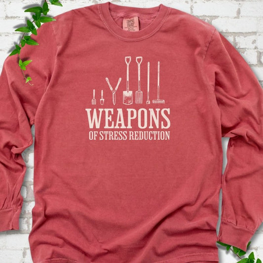 Crimson Comfort Colors® long sleeve T-shirt flat lay featuring garden tools and the words “Weapons of Stress Reduction.”