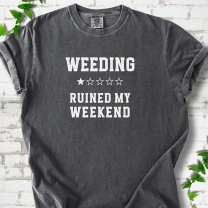 Pepper short sleeve T-shirt laid flat on white brick with greenery, showing cream 'Weeding Ruined My Weekend' lettering and a one-star rating on the chest.