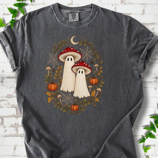 Pepper Comfort Colors® T-shirt laid flat, showing two cream ghosts wearing red mushroom caps, surrounded by small pumpkins, autumn leaves and a crescent moon.