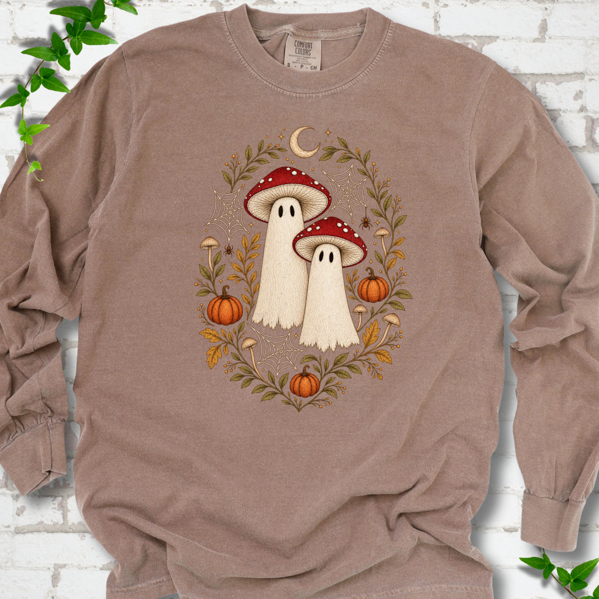 Espresso Comfort Colors® long sleeve T-shirt laid flat, showing two cream ghosts wearing red mushroom caps, surrounded by small pumpkins, autumn leaves and a crescent moon.