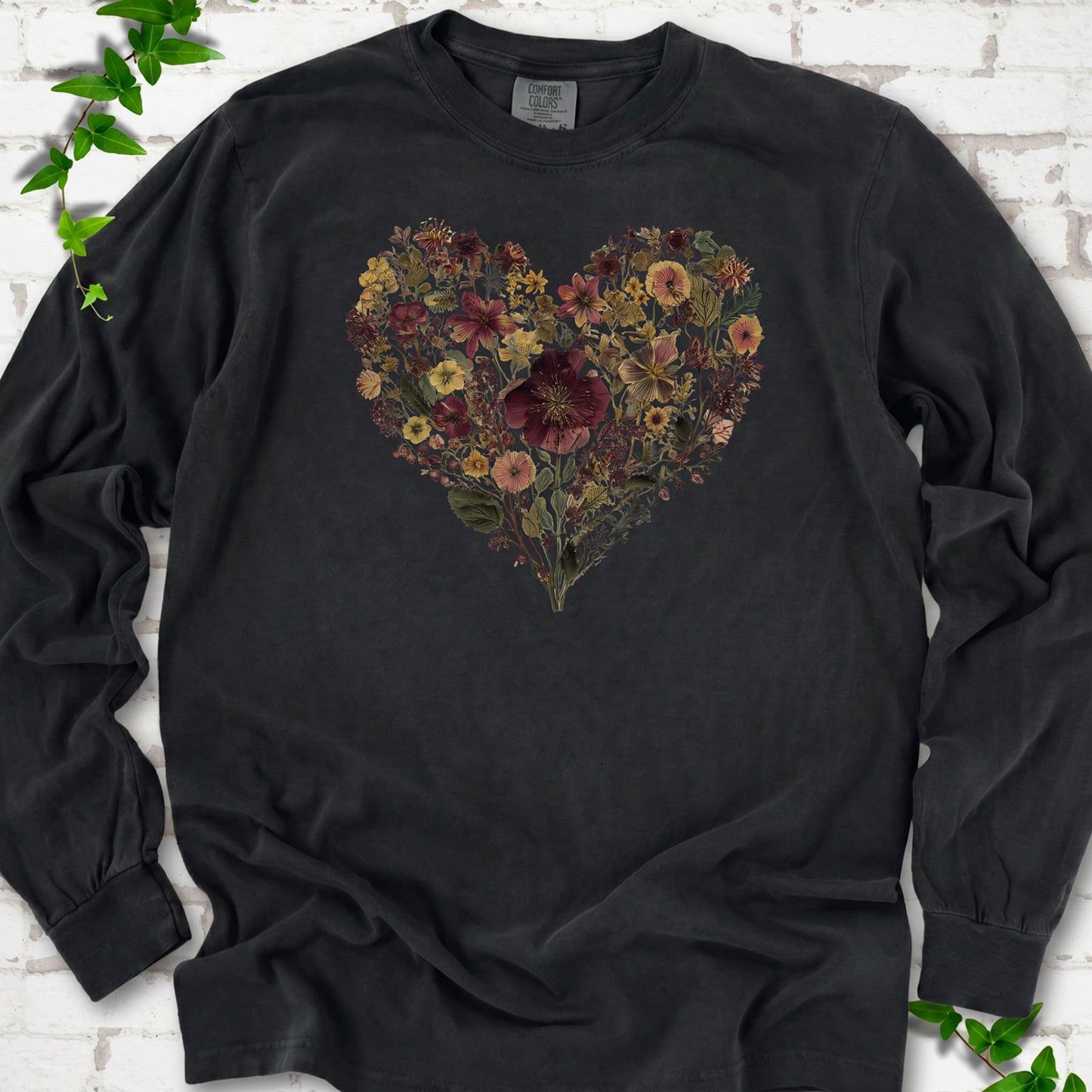 Black Comfort Colors® long sleeve T-shirt flat lay featuring a heart formed from delicate wildflowers.