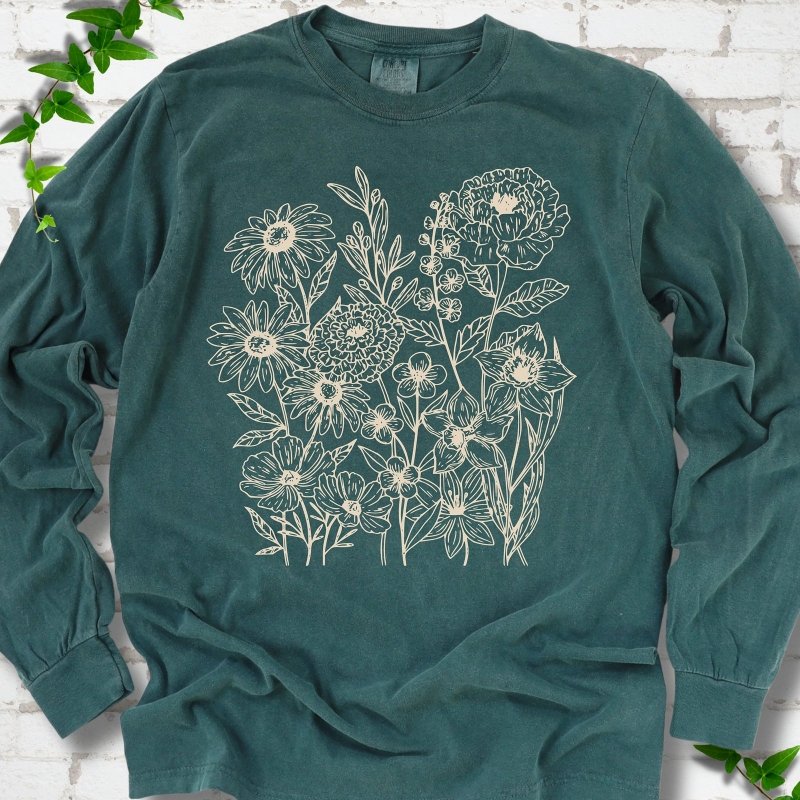 Blue Spruce Comfort Colors® long sleeve T-shirt flat lay featuring delicate cream wildflower line art.