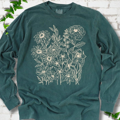 Blue Spruce Comfort Colors® long sleeve T-shirt flat lay featuring delicate cream wildflower line art.