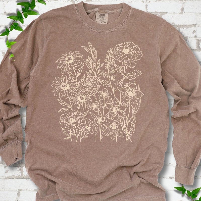 Espresso Comfort Colors® long sleeve T-shirt flat lay featuring delicate cream wildflower line art.