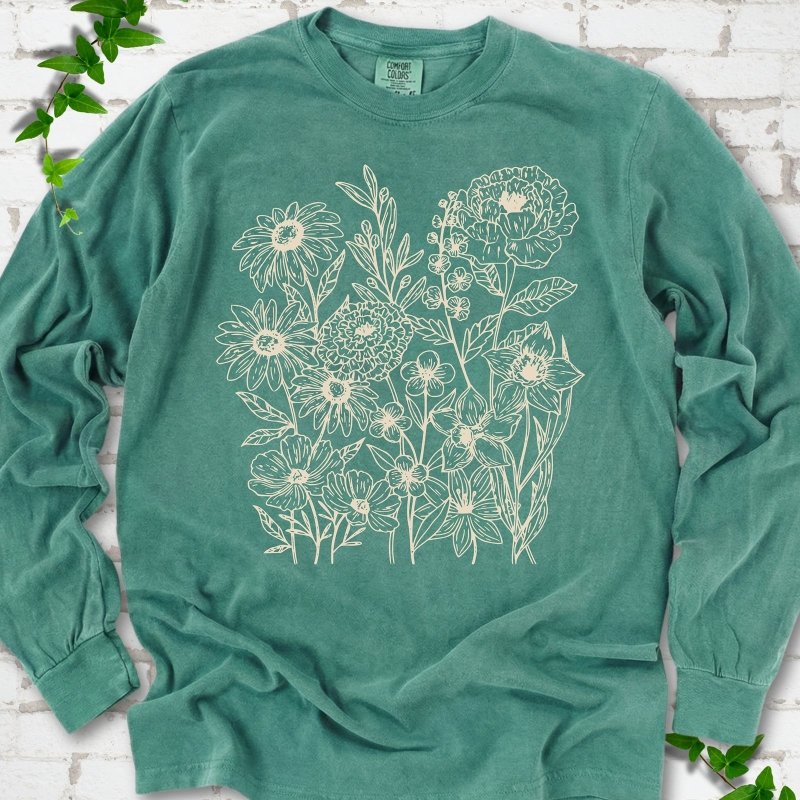 Light Green Comfort Colors® long sleeve T-shirt flat lay featuring delicate cream wildflower line art.