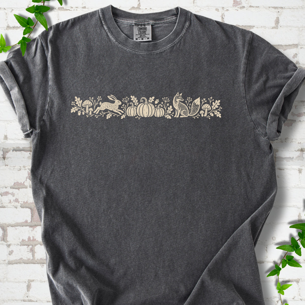 Pepper Comfort Colors® T-shirt with a folk-style Woodland Harvest design of mushrooms, pumpkins and woodland animals.