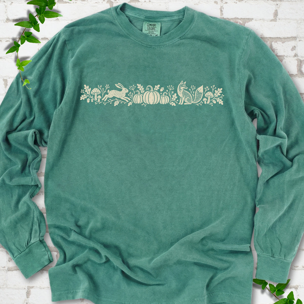 Light Green Comfort Colors® long sleeve shirt with a folk-style Woodland Harvest design of mushrooms, pumpkins and woodland animals.
