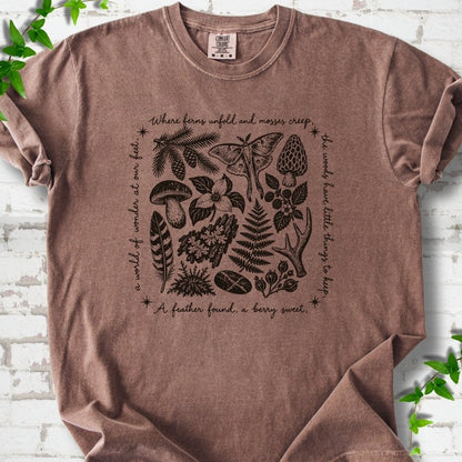 Espresso brown short-sleeve tee with woodland finds engraving in dark brown ink, framed by "a world of wonder at our feet".