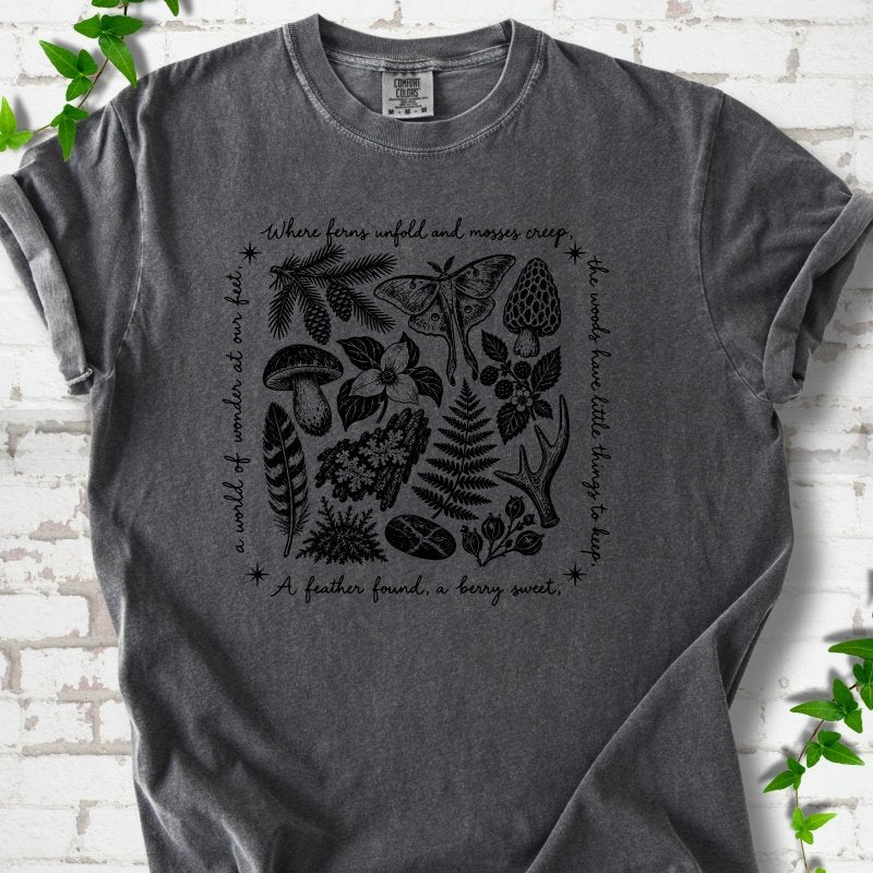 Pepper gray short-sleeve tee with woodland finds engraving in black ink, framed by "a world of wonder at our feet".