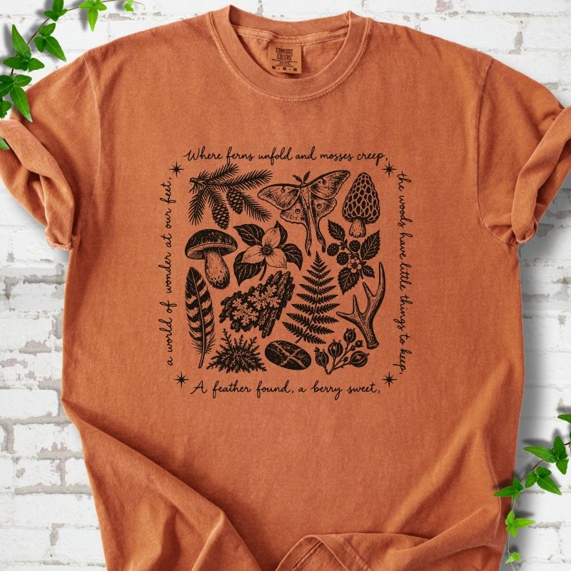 Yam orange short-sleeve tee with woodland finds engraving in black ink, framed by "a world of wonder at our feet".