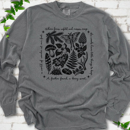 Pepper gray long-sleeve tee with woodland finds engraving in black ink, framed by "a world of wonder at our feet".