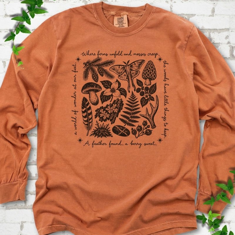 Yam orange long-sleeve tee with woodland finds engraving in black ink, framed by "a world of wonder at our feet".