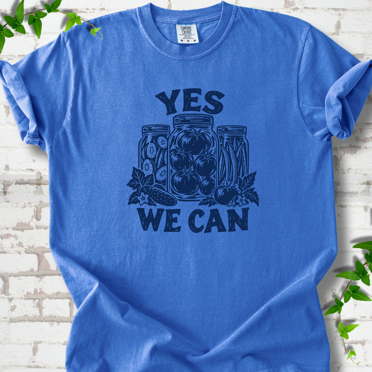 Flo Blue Comfort Colors® T-shirt flat lay featuring preserved tomatoes in jars and the words “Yes We Can.”
