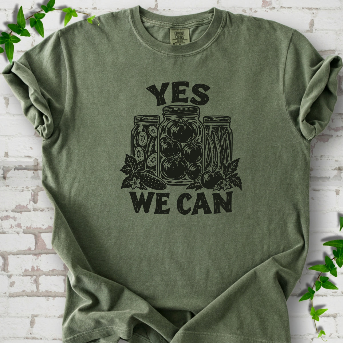 Moss Comfort Colors® T-shirt flat lay featuring preserved tomatoes in jars and the words “Yes We Can.”