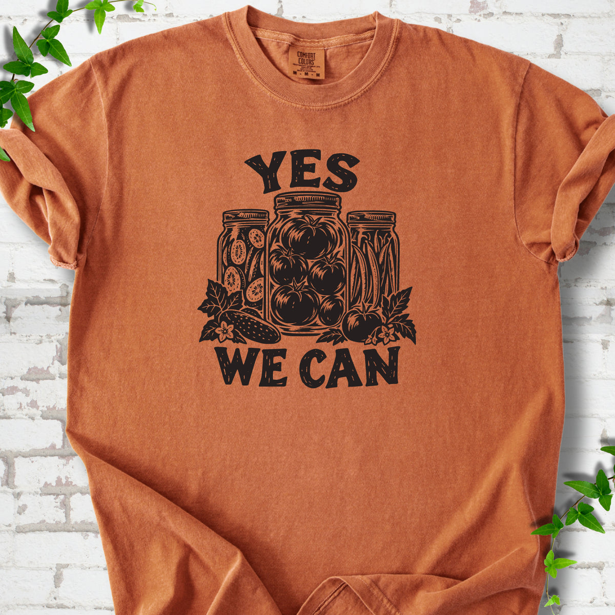 Yam Comfort Colors® T-shirt flat lay featuring preserved tomatoes in jars and the words “Yes We Can.”