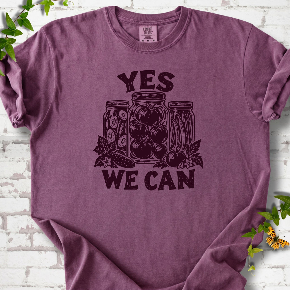 Berry Comfort Colors® T-shirt flat lay featuring preserved tomatoes in jars and the words “Yes We Can.”
