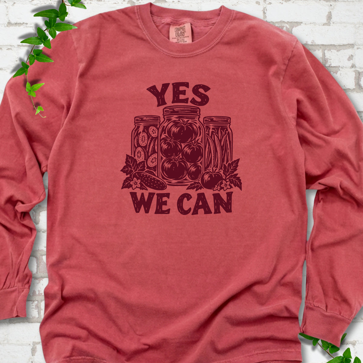 Crimson Comfort Colors® long sleeve T-shirt flat lay featuring preserved tomatoes in jars and the words “Yes We Can.”