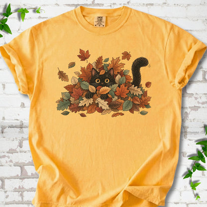 Citrus Comfort Colors® T-shirt flat lay featuring a black cat peeking from a pile of orange and green autumn leaves.