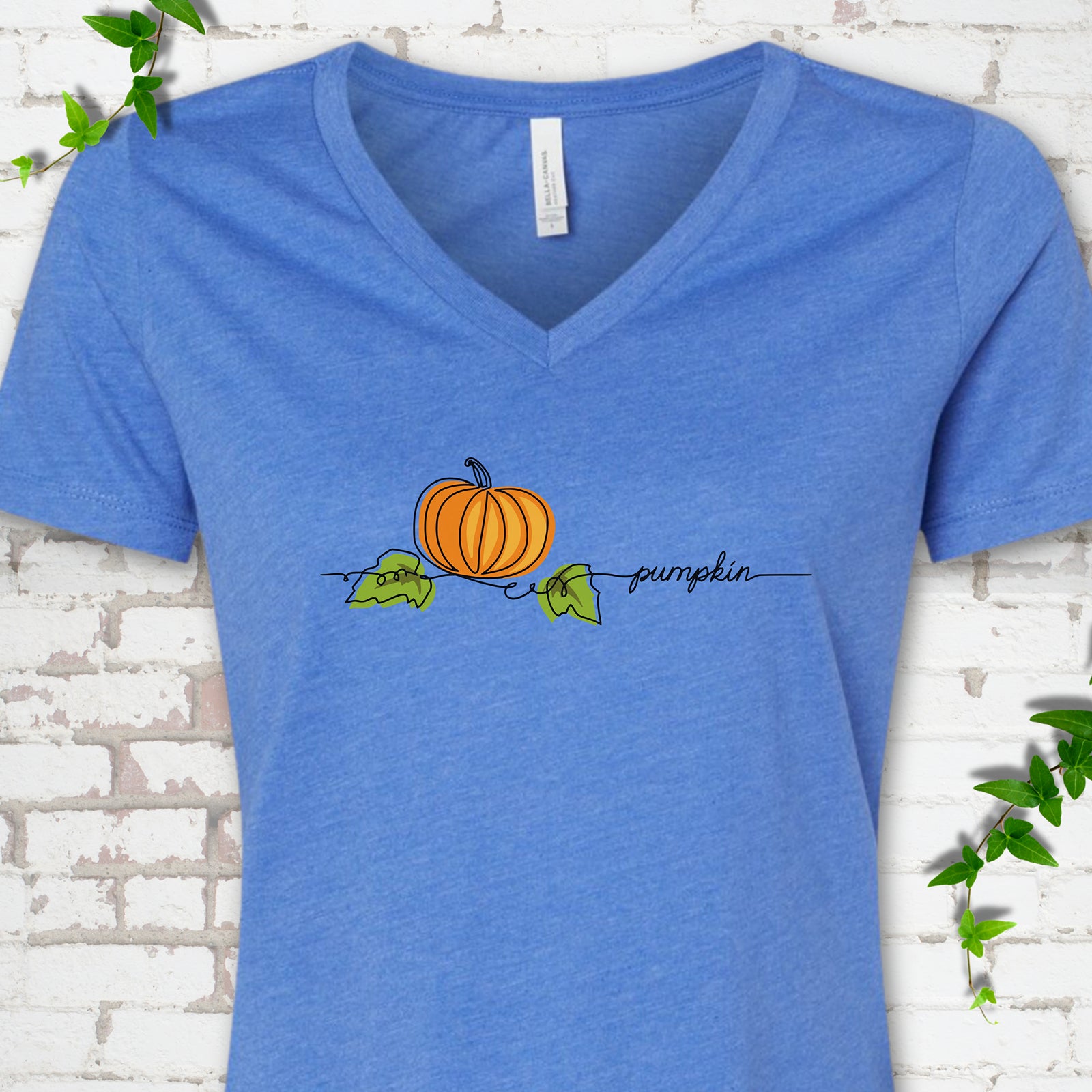 Heather True Royal Bella Canvas® V-neck T-shirt flat lay featuring a minimalist orange pumpkin, green leaves and delicate black script.