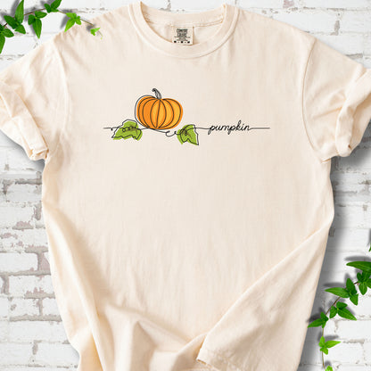 Ivory Comfort Colors® T-shirt flat lay featuring a minimalist orange pumpkin, green leaves and delicate black script.
