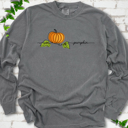 Pepper Comfort Colors® long sleeve T-shirt flat lay featuring a minimalist orange pumpkin, green leaves and delicate black script.