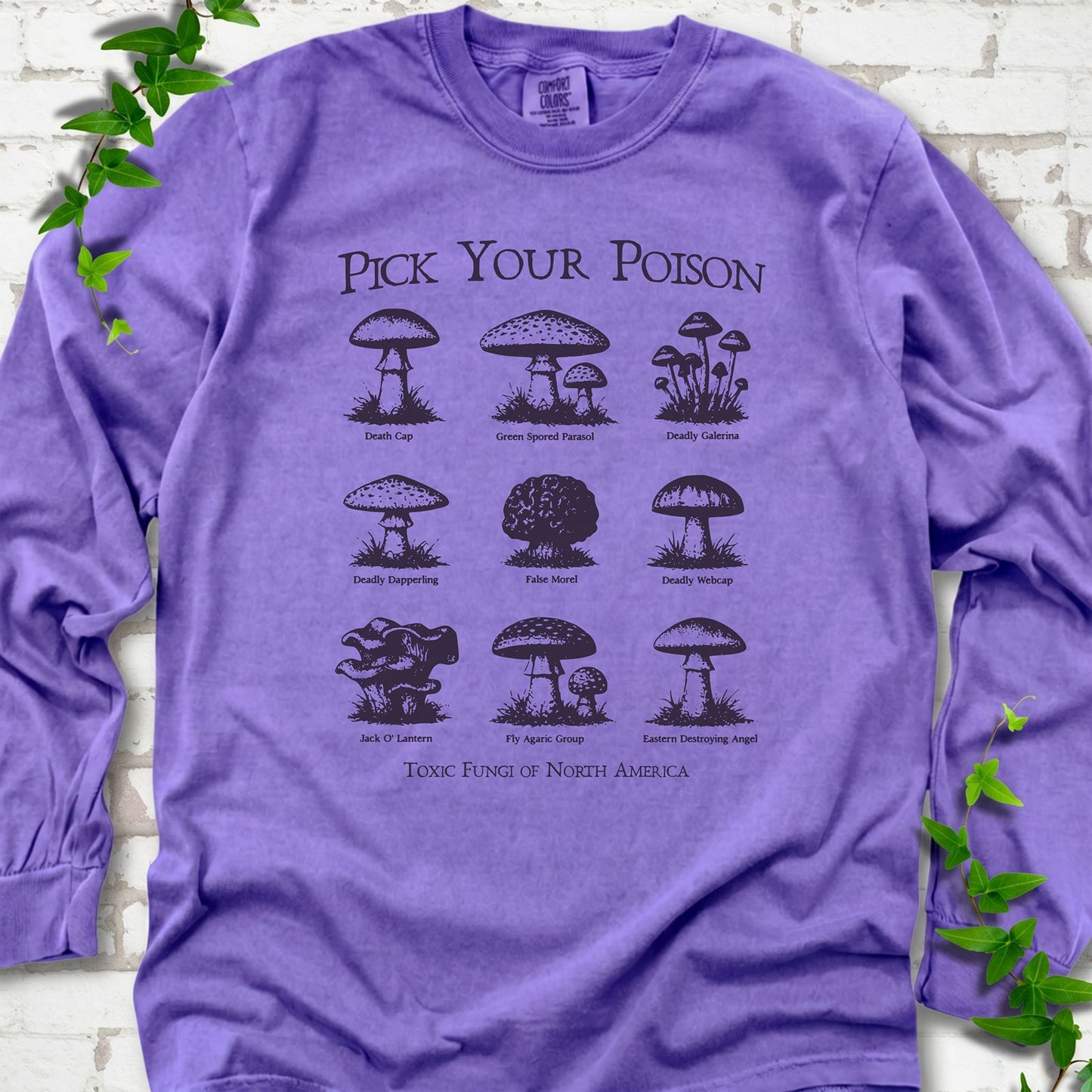 Violet Comfort Colors® long sleeve T-shirt flat lay featuring a Pick Your Poison field guide of toxic North American mushrooms.