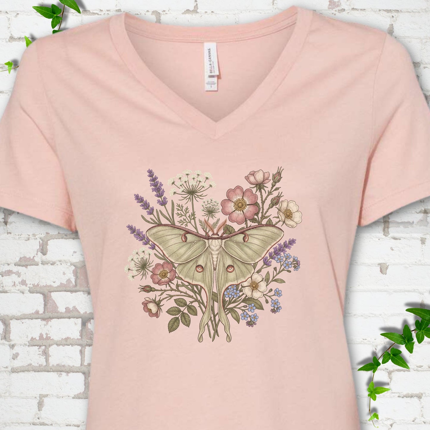 Heather Peach Bella Canvas® V-neck T-shirt flat lay featuring a pale luna moth surrounded by pink, lavender, blue and white wildflowers.