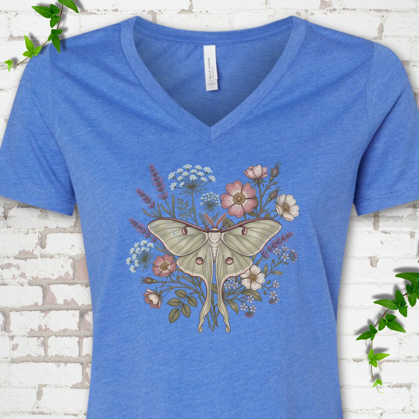 Heather True Royal Bella Canvas® V-neck T-shirt flat lay featuring a pale luna moth surrounded by pink, lavender, blue and white wildflowers.