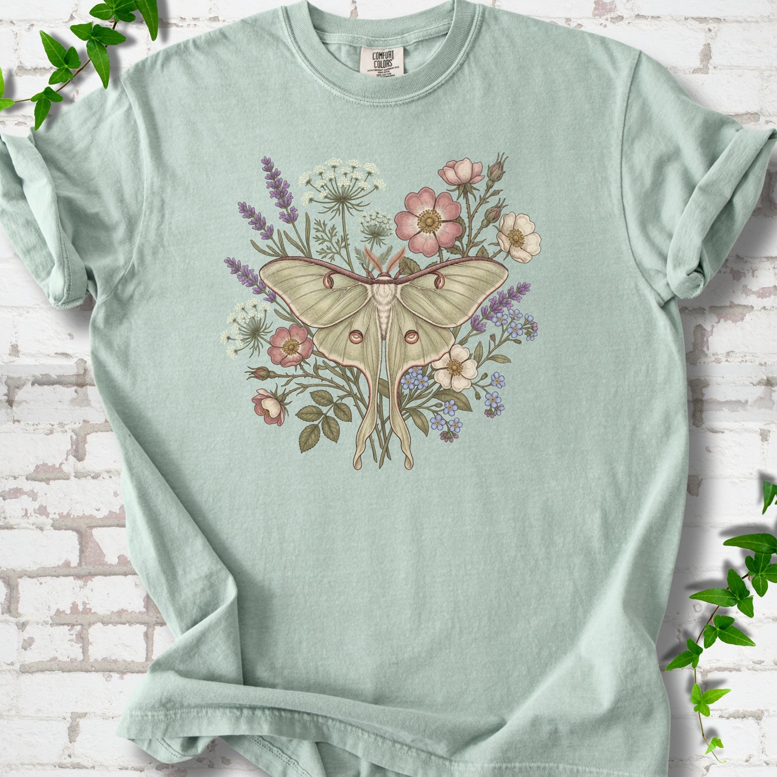 Bay Comfort Colors® T-shirt flat lay featuring a pale luna moth surrounded by pink, lavender, blue and white wildflowers.