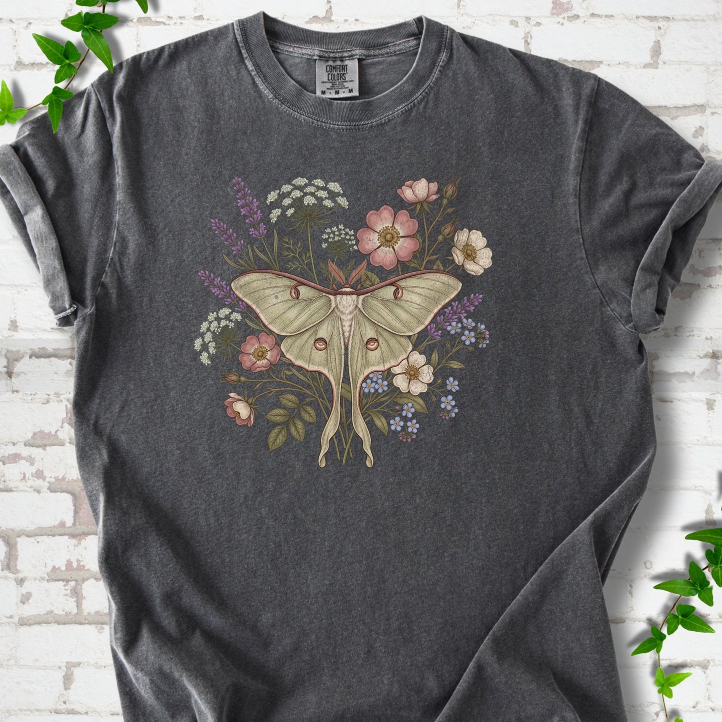 Pepper Comfort Colors® T-shirt flat lay featuring a pale luna moth surrounded by pink, lavender, blue and white wildflowers.