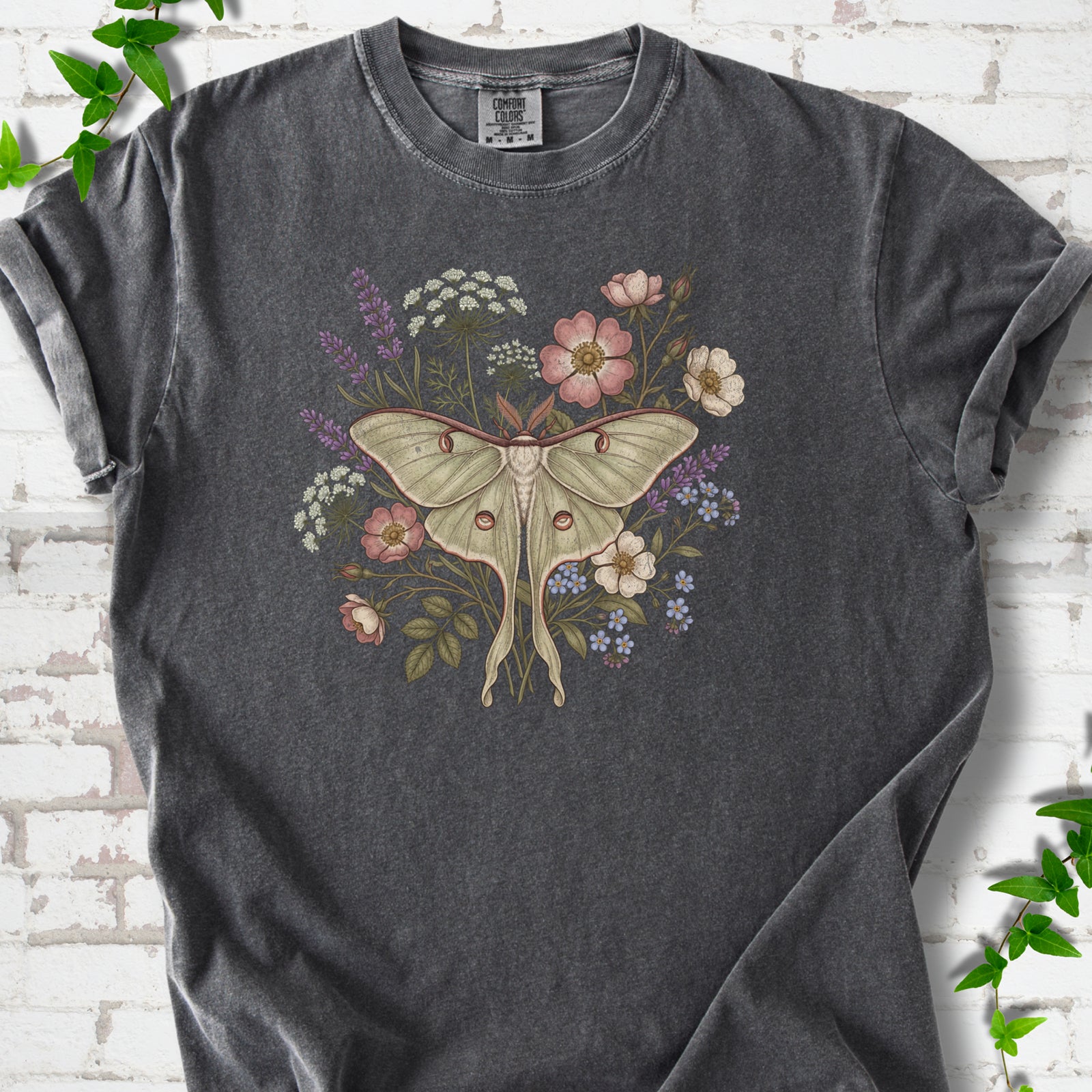 Pepper Comfort Colors® T-shirt flat lay featuring a pale luna moth surrounded by pink, lavender, blue and white wildflowers.