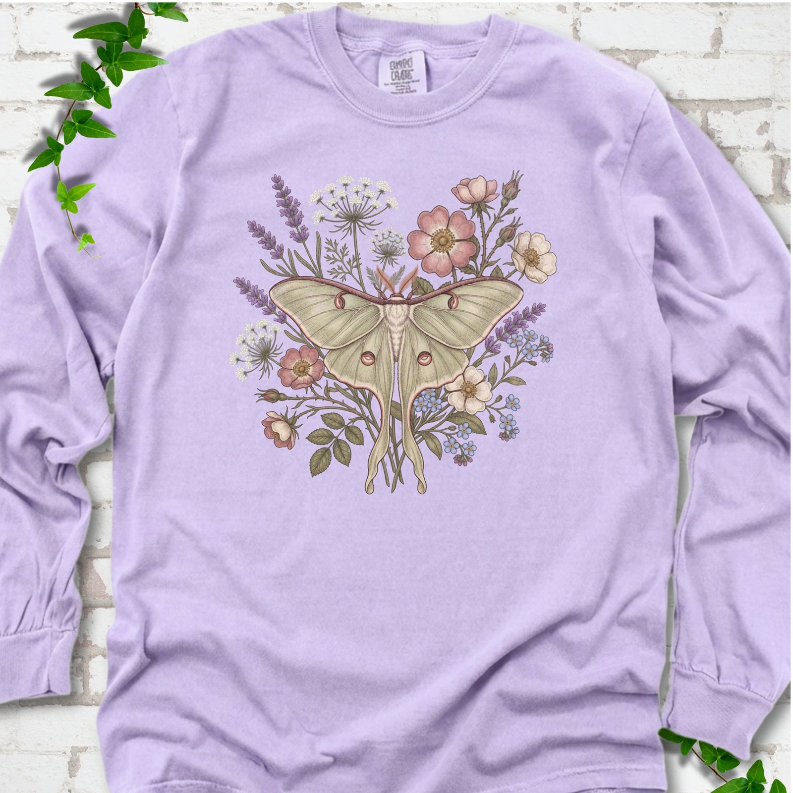 Orchid Comfort Colors® long sleeve T-shirt flat lay featuring a pale luna moth surrounded by pink, lavender, blue and white wildflowers.