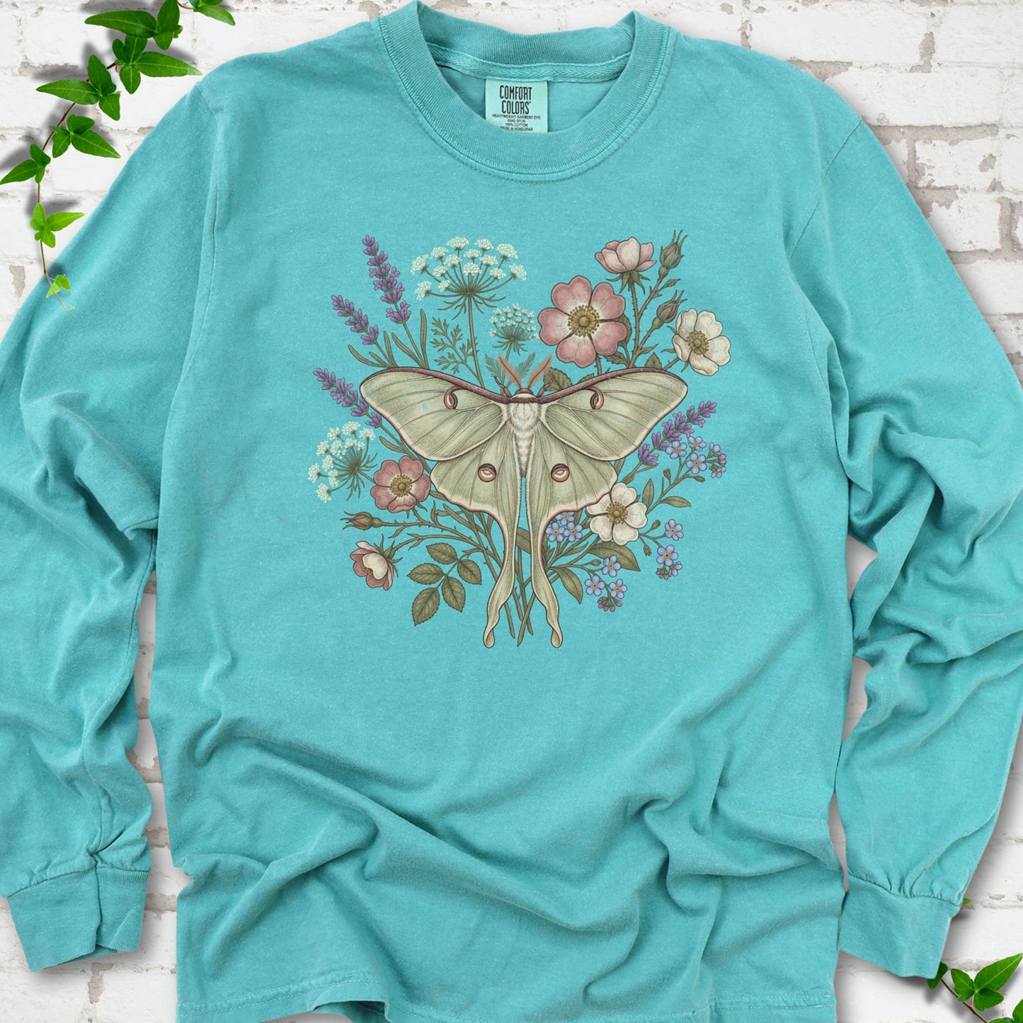 Seafoam Comfort Colors® long sleeve T-shirt flat lay featuring a pale luna moth surrounded by pink, lavender, blue and white wildflowers.