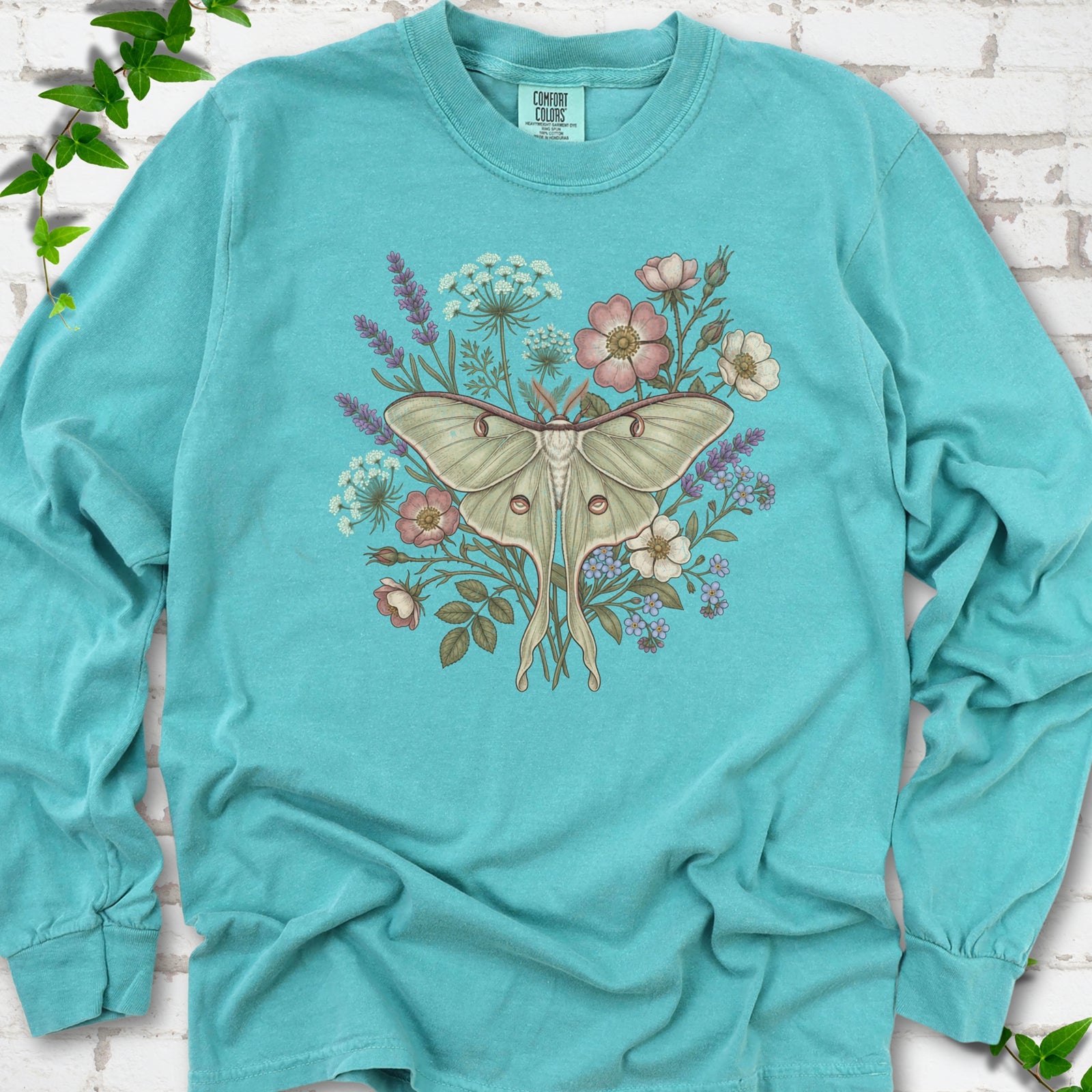 Seafoam Comfort Colors® long sleeve T-shirt flat lay featuring a pale luna moth surrounded by pink, lavender, blue and white wildflowers.